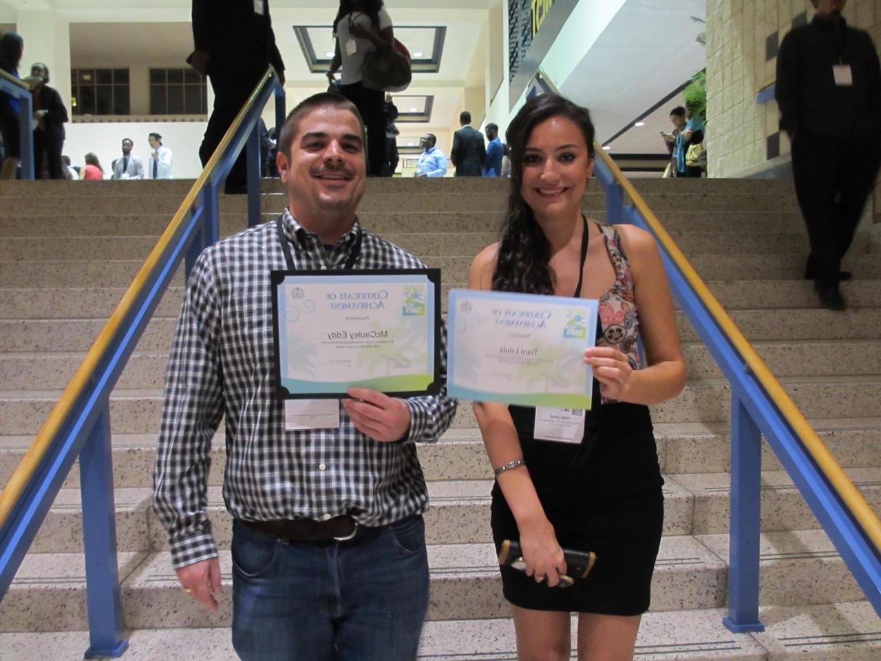 Two students proudly holding Certificates of Acheivement
